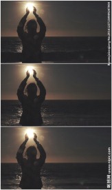 女孩海边双手托举落日